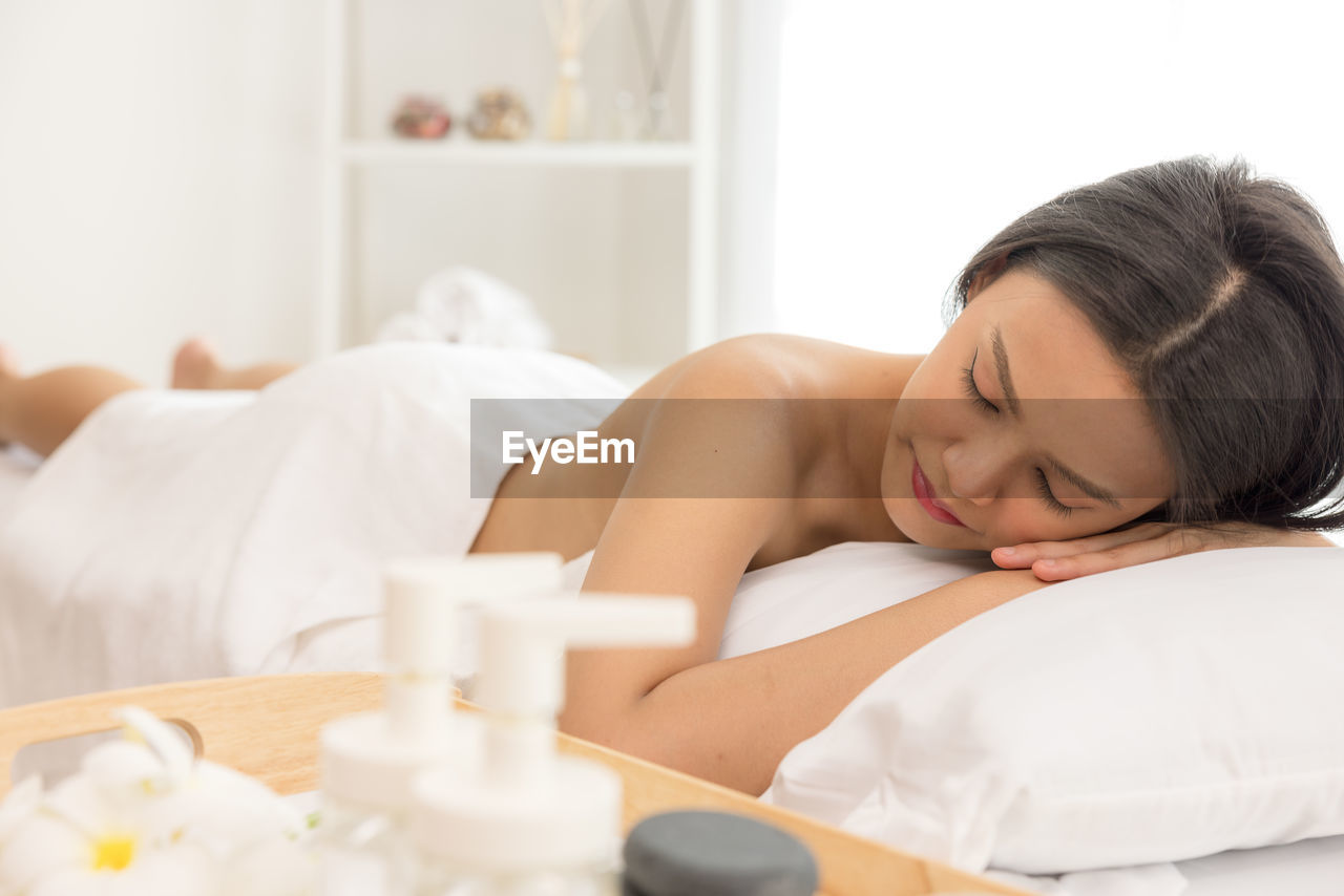 In a spa salon, a young woman enjoys massage therapy.