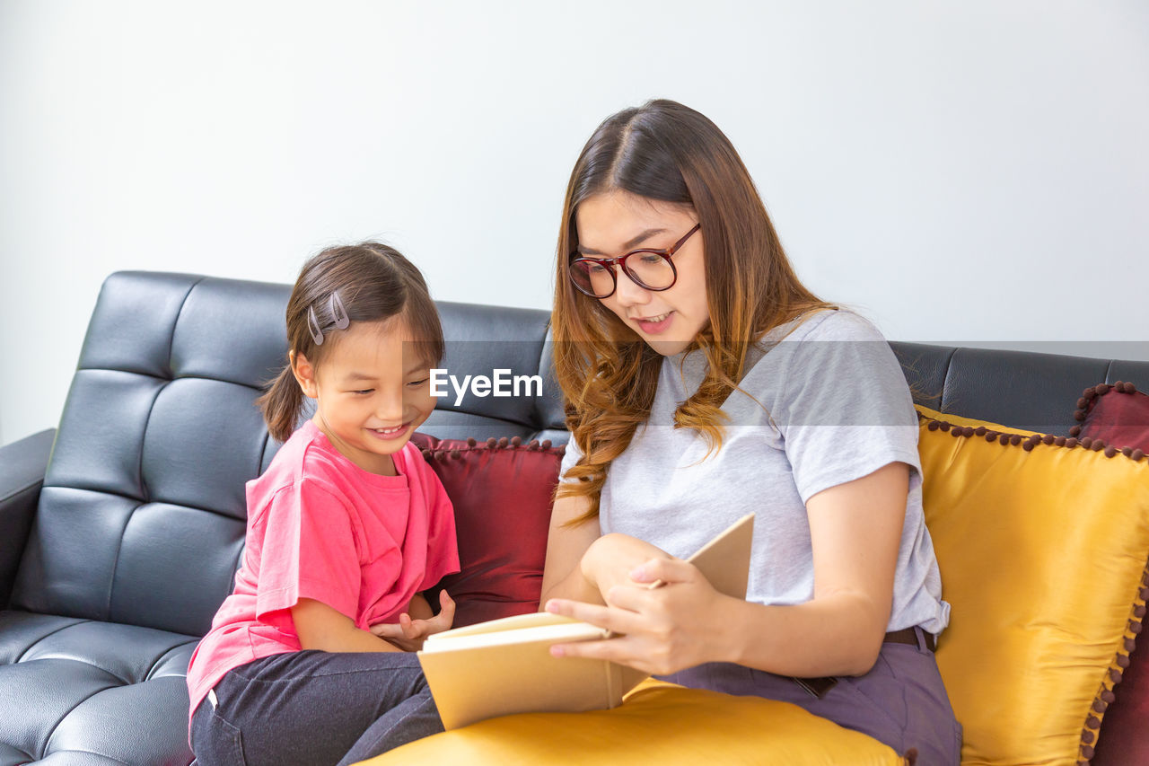 Woman teaching daughter while sitting at home