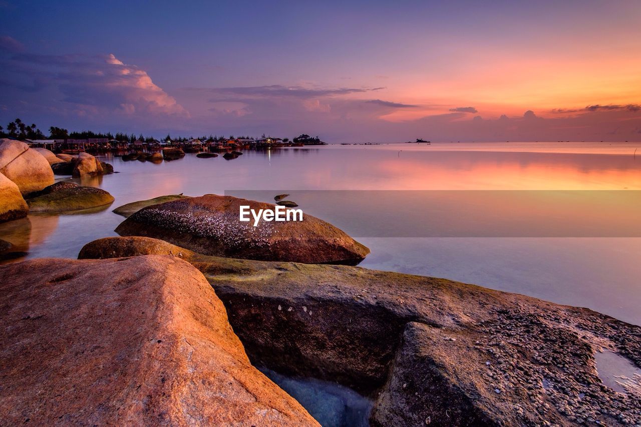 Rocks in sea at sunset