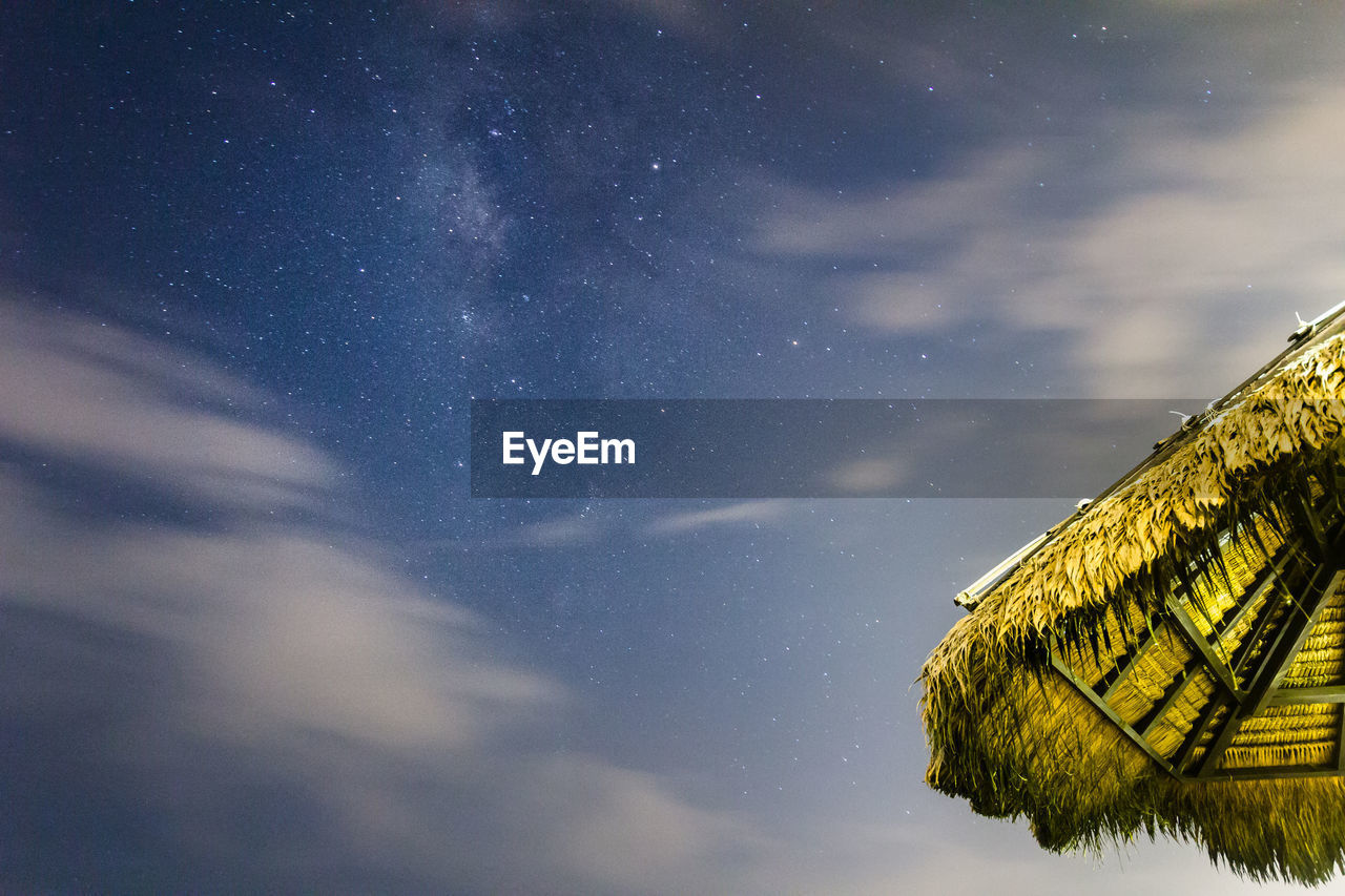 Low angle view of thatched roof against sky at night