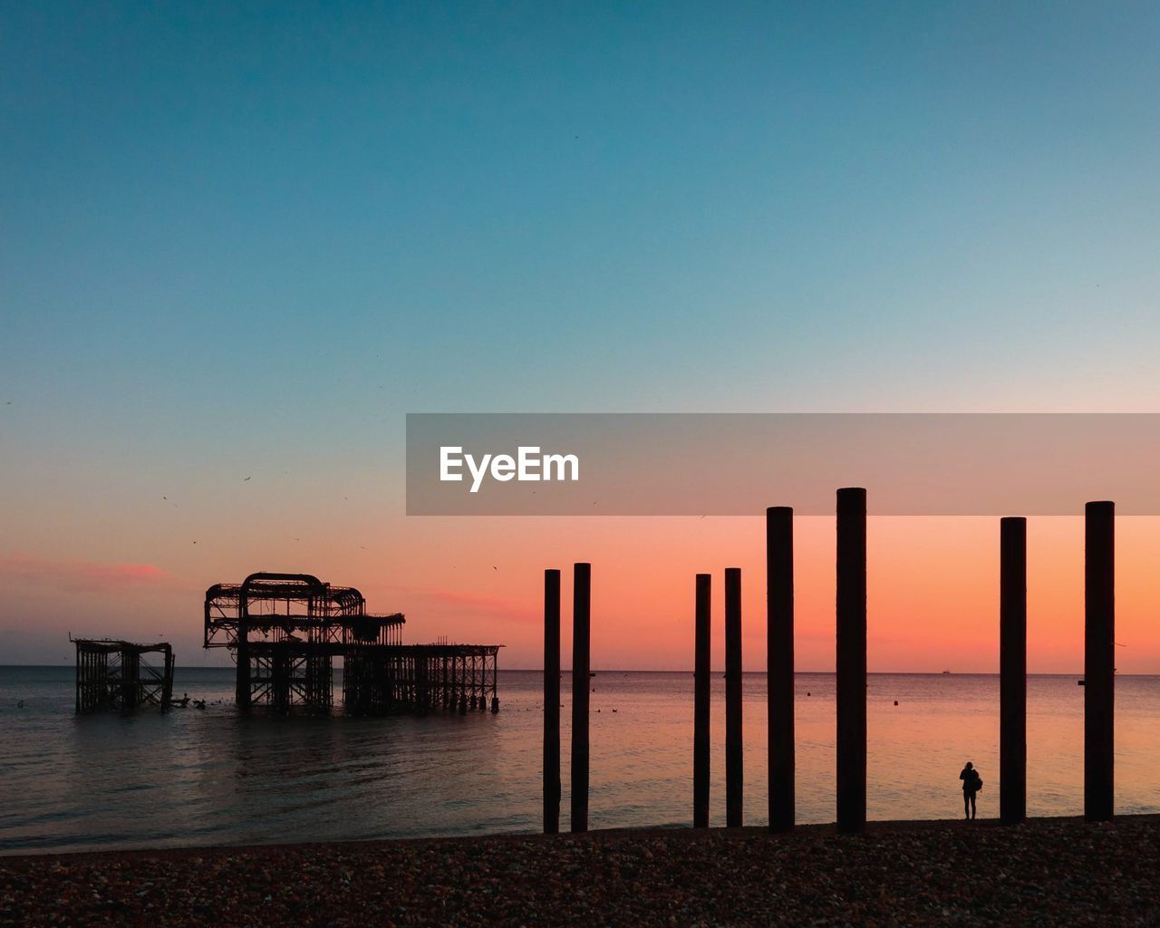Pier on sea against clear sky during sunset