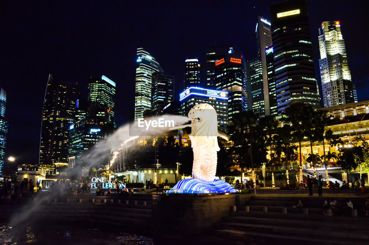 Illuminated fountain at city against sky at night