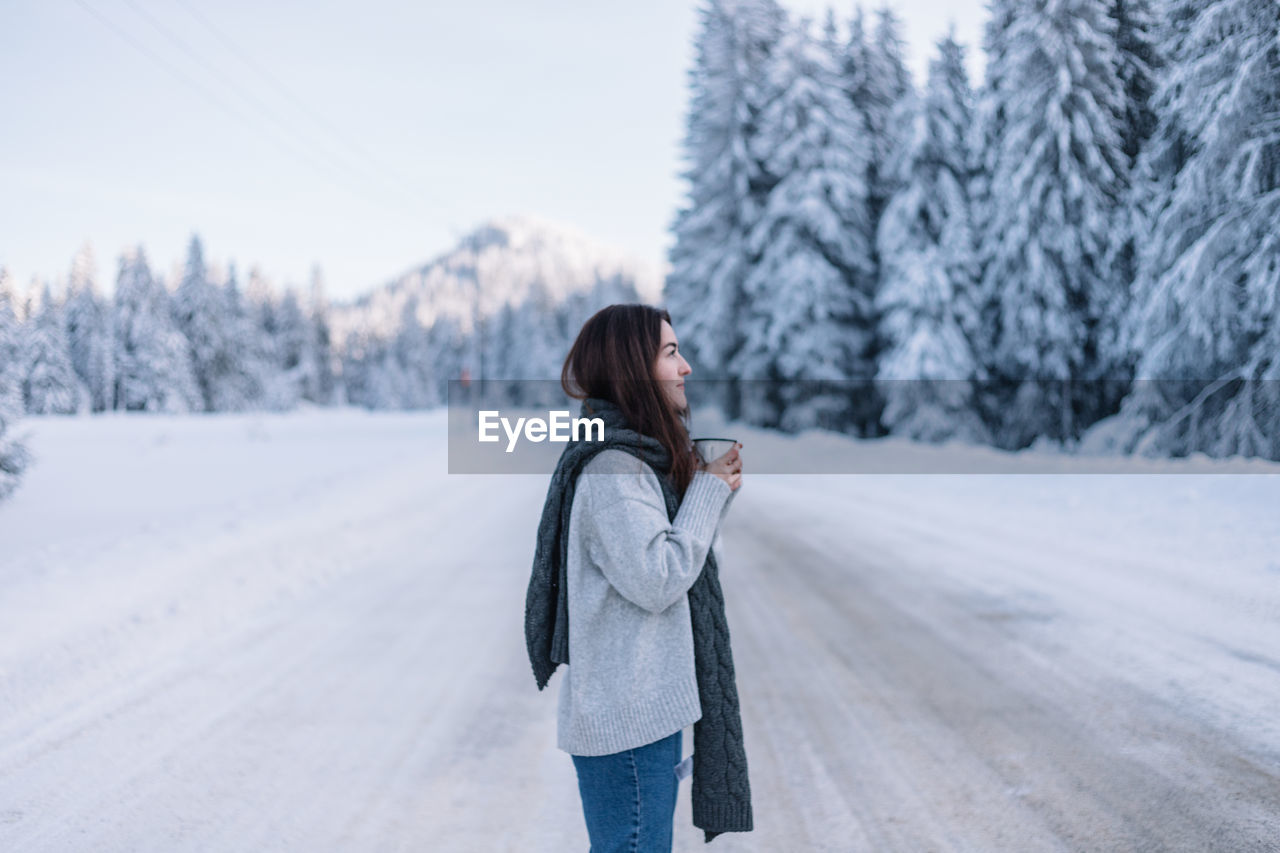 Woman drinking hot tea while on a road trip during winter.