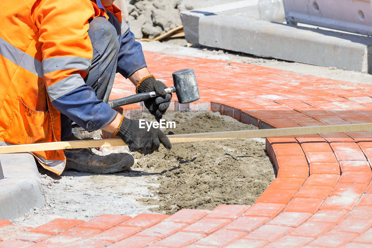 working, occupation, asphalt, floor, one person, manual worker, industry, men, road surface, protection, adult, construction industry, roof, protective workwear, flooring, bricklayer, work tool, construction worker, construction site, reflective clothing, equipment, business finance and industry, road construction, day, clothing, holding, orange color, outdoors, technology