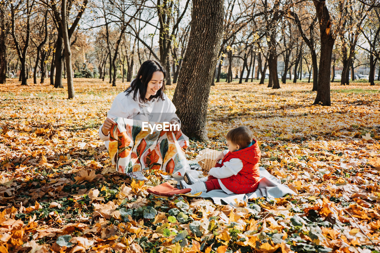 Happy family mother and little toddler baby daughter having fun together in autumn picnic