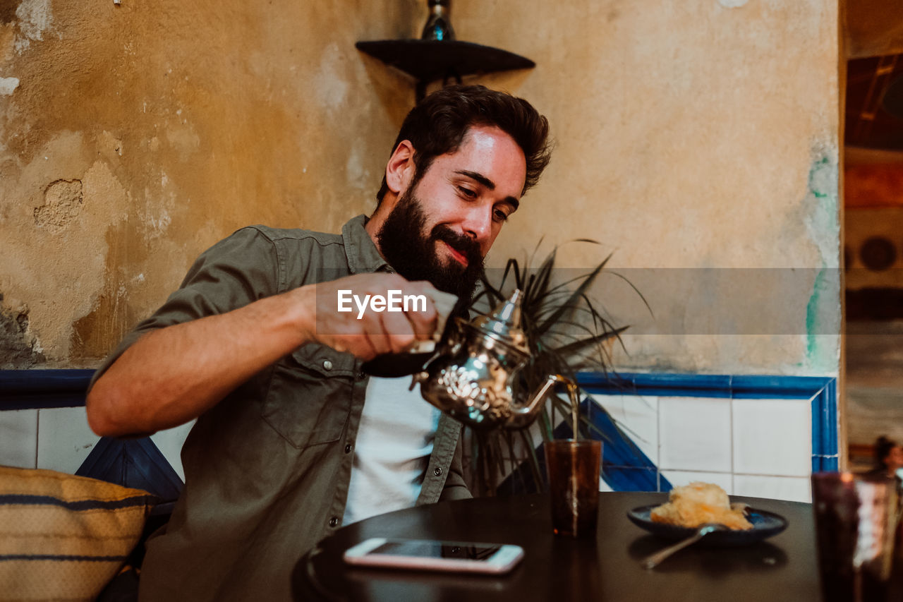 Man poring drink in glass on table