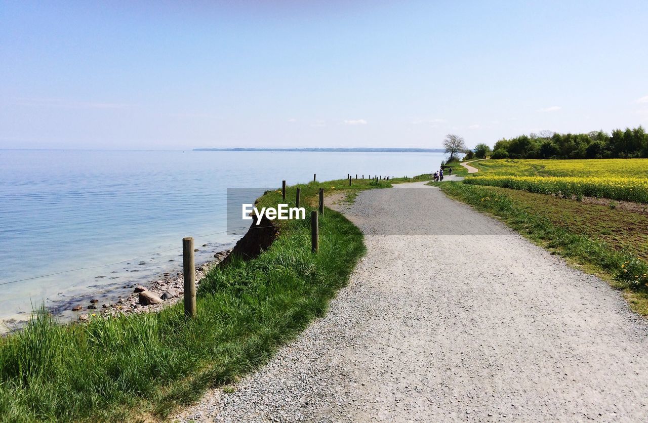 Scenic view of road by sea against sky