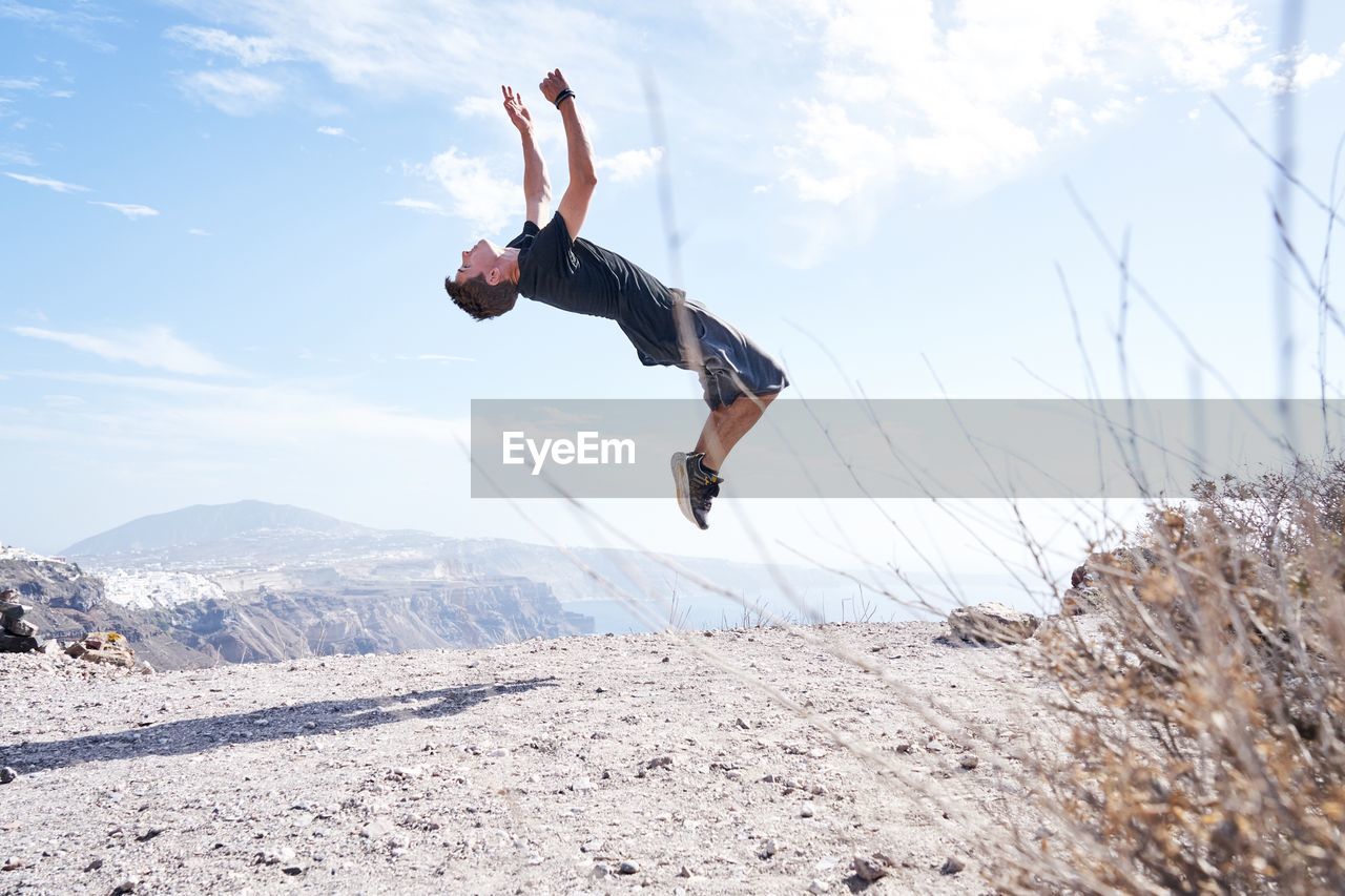 FULL LENGTH OF MAN JUMPING AGAINST MOUNTAIN