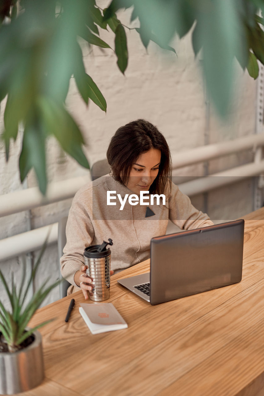 High angle view of woman using laptop at cafe