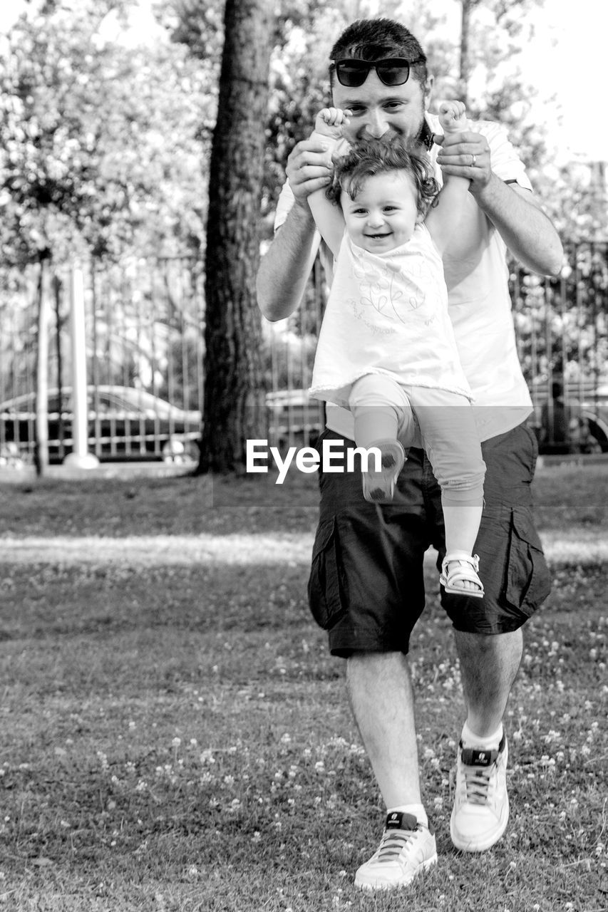 Smiling man playing with daughter in park