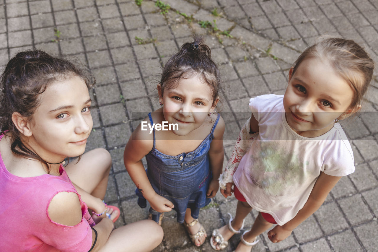 Three smiling little girls look into the camera outdoors