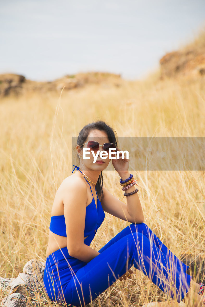 Portrait of young woman sitting on field