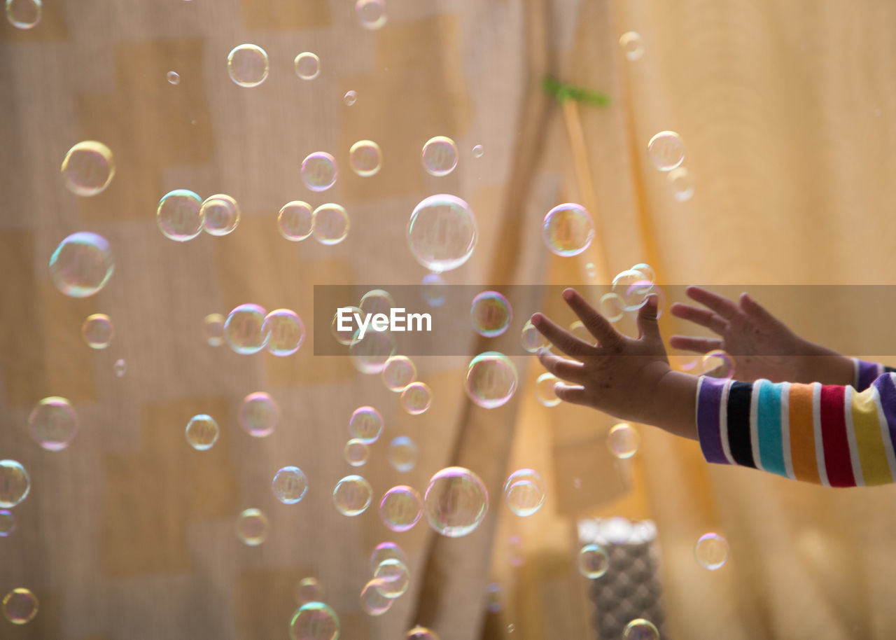 Cropped hands of child by bubbles