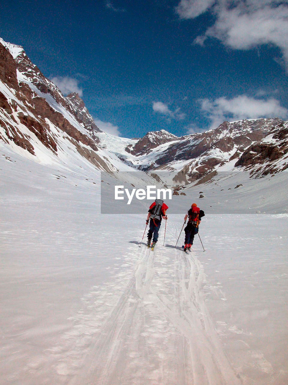 PEOPLE SKIING ON SNOWCAPPED MOUNTAIN AGAINST SKY