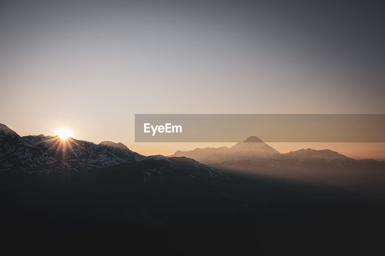 Scenic view of silhouette mountains against clear sky during sunset