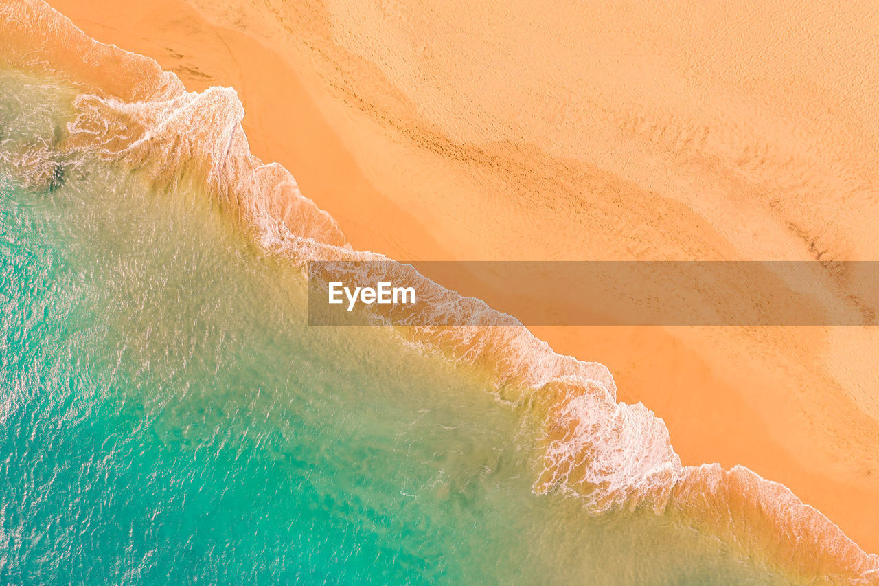 Aerial view of atlantic ocean coast with crystal clear turquoise water, waves rolling into the shore