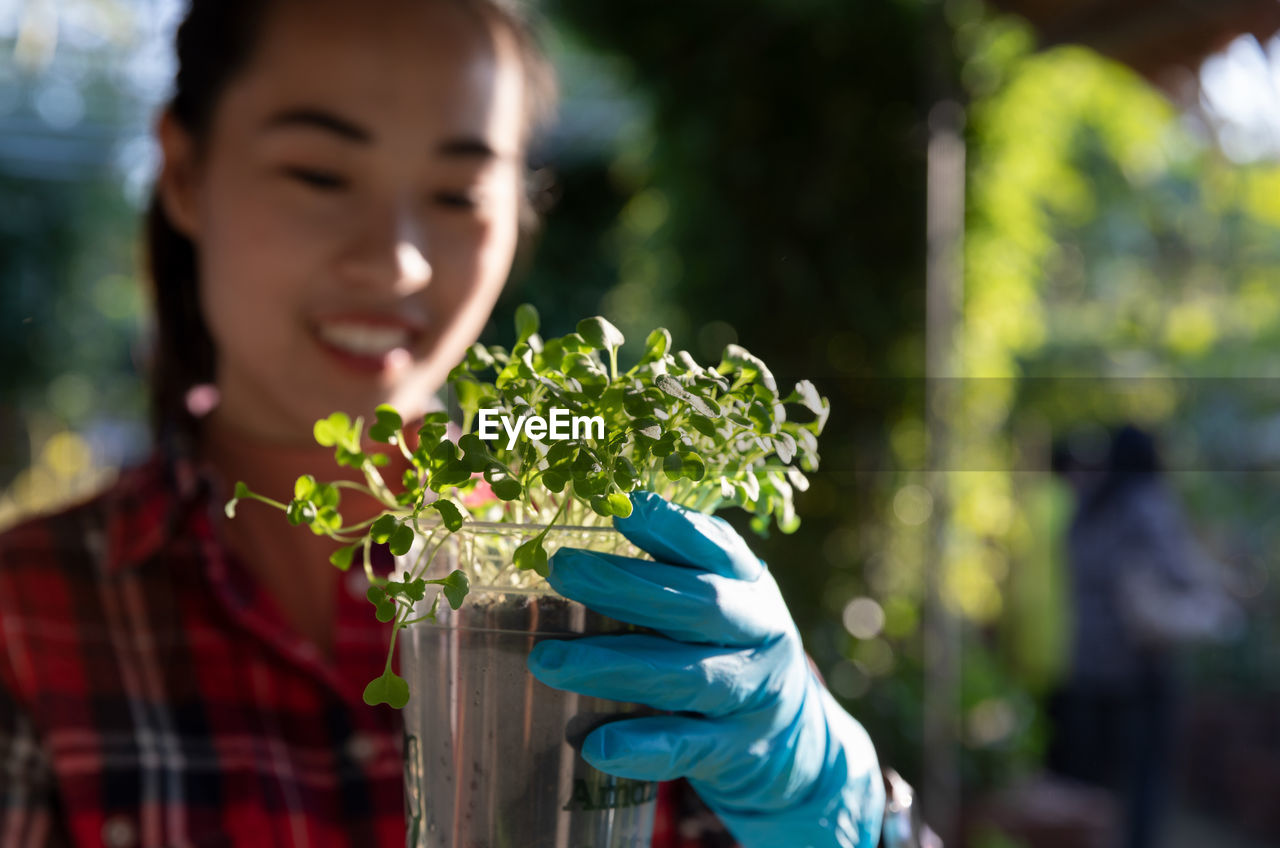 Young woman holding plants in nursery