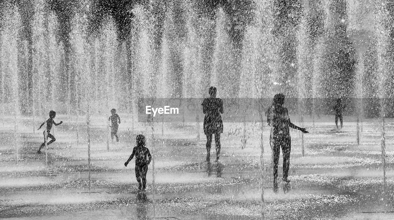 Silhouette people enjoying fountains