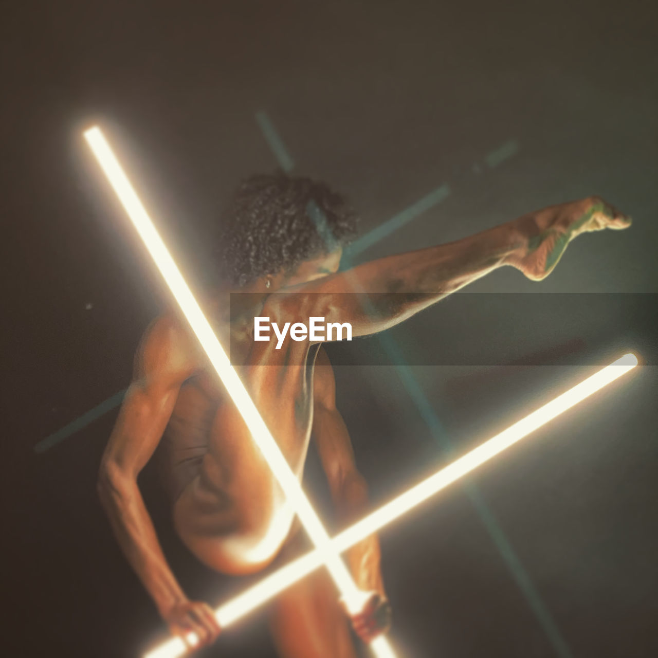 Naked woman with illuminated lighting equipment against gray background