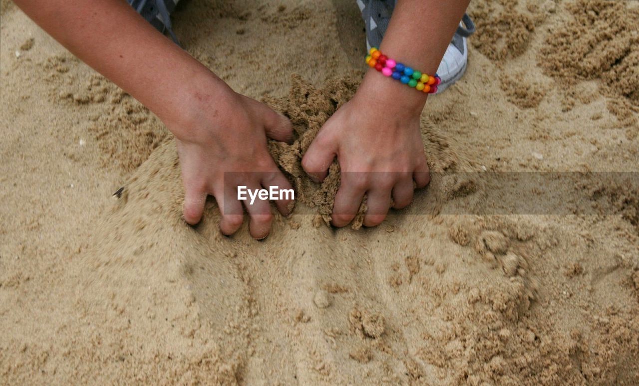 LOW SECTION OF CHILDREN PLAYING ON SAND