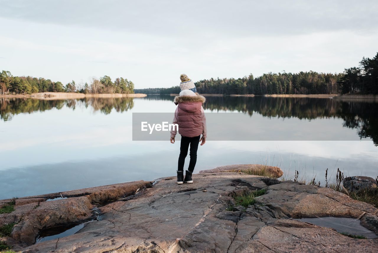 Young girl stood on the rocks enjoying the beautiful reflection