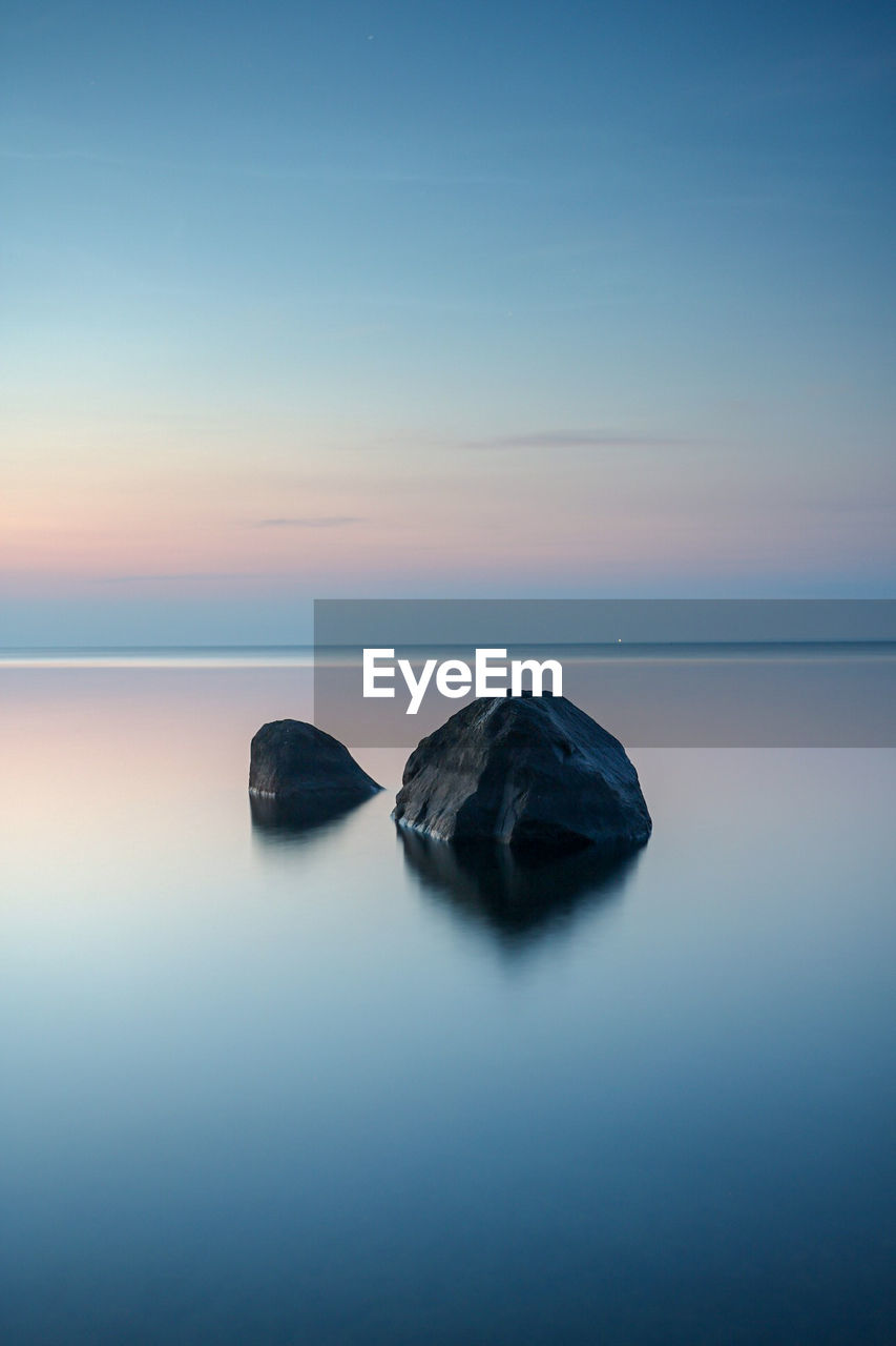 Rocks on sea against sky during sunset