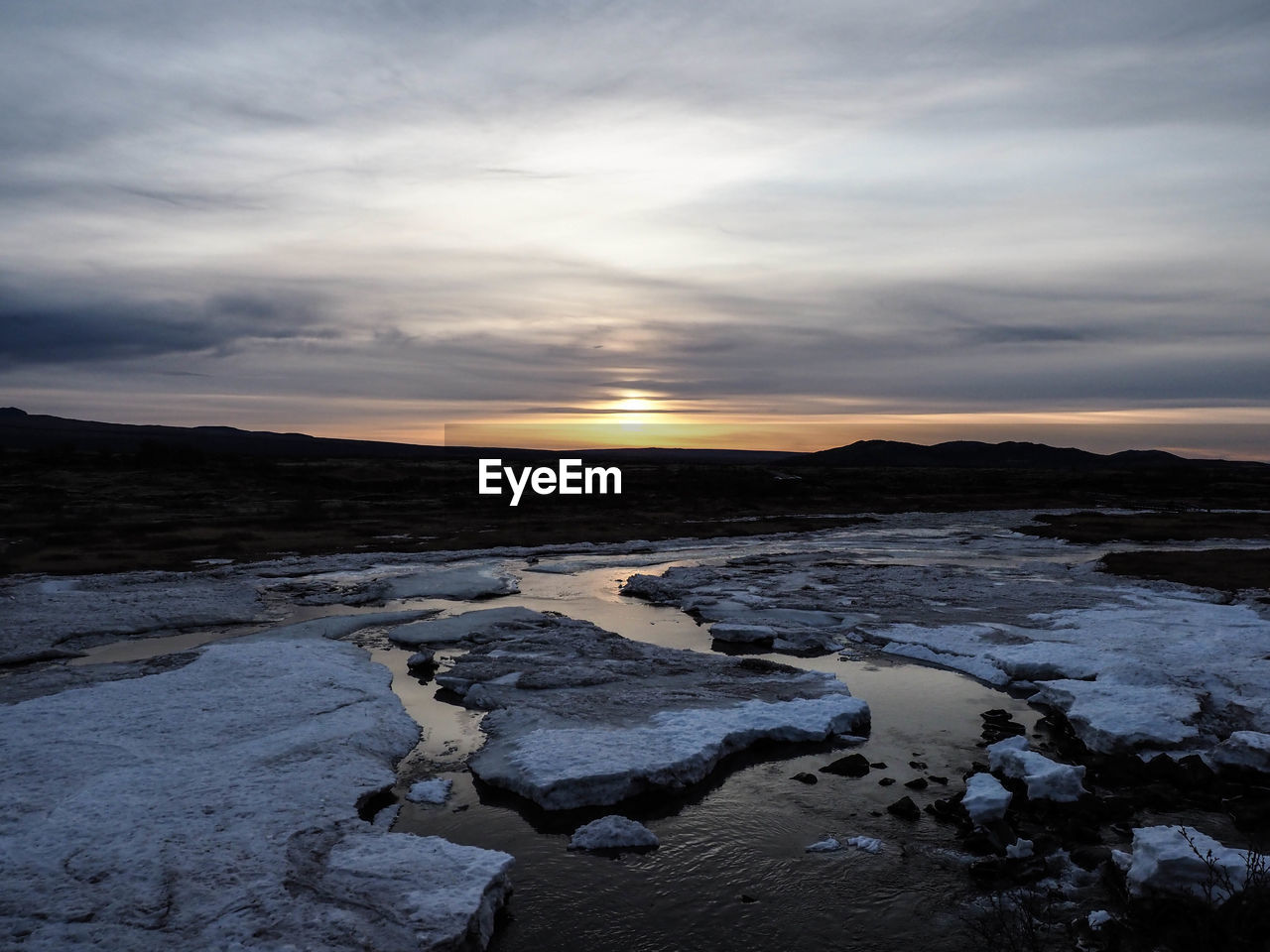 Scenic view of frozen sea against sky during sunset