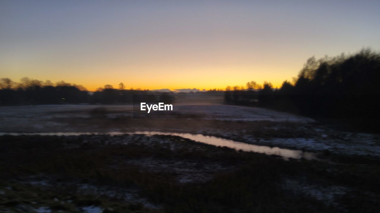 SCENIC VIEW OF FROZEN RIVER AGAINST SKY DURING SUNSET