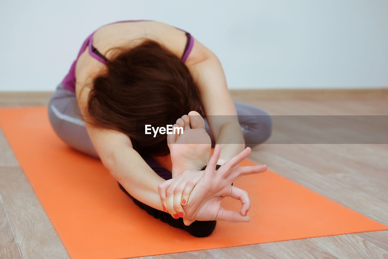 MIDSECTION OF WOMAN SITTING ON FLOOR