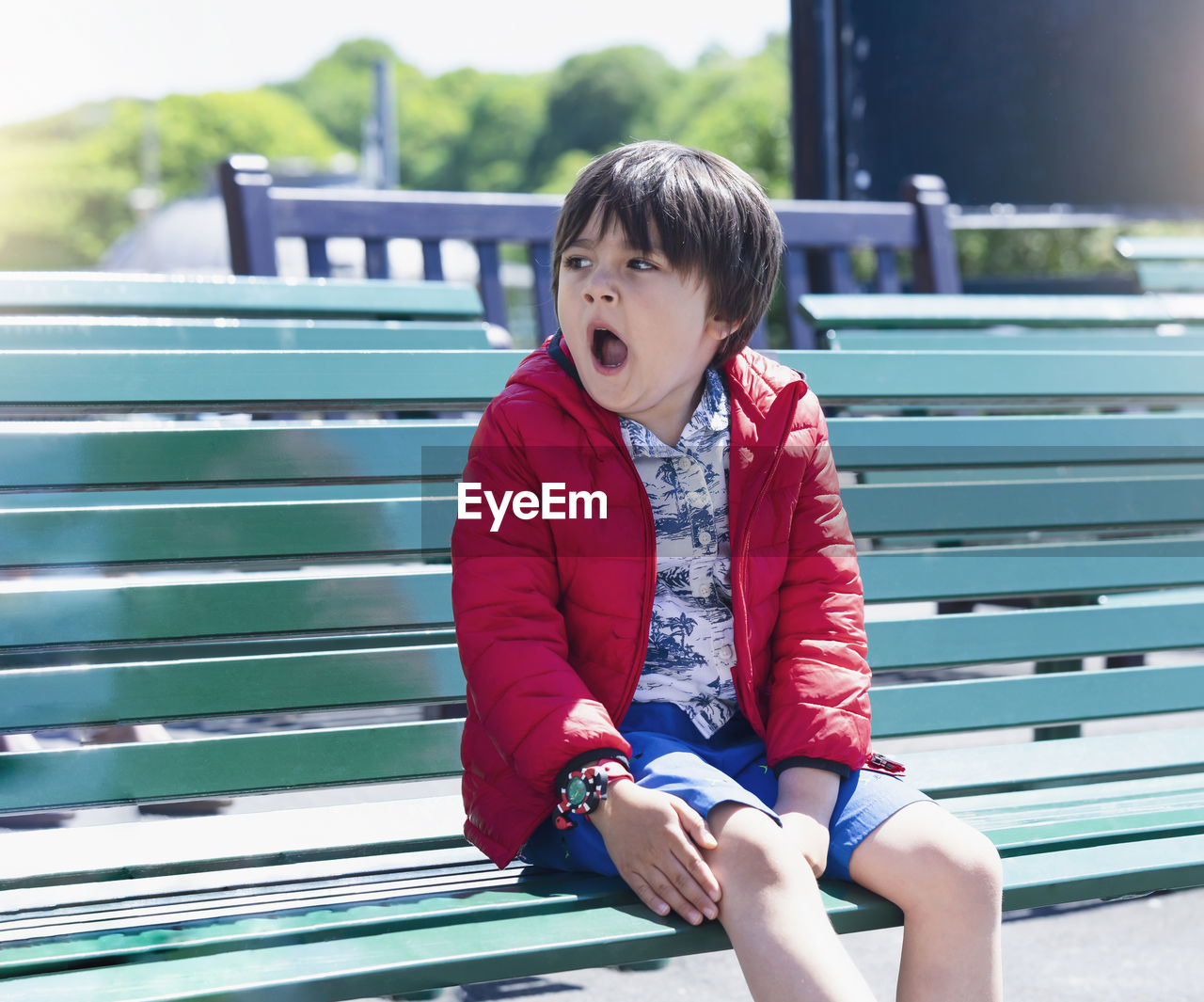 Boy yawning while sitting on bench