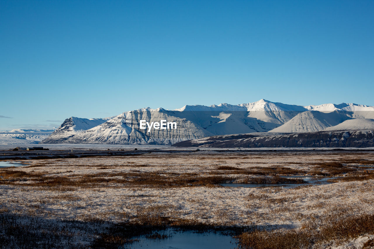 Scenic view of snowcapped mountains against clear blue sky