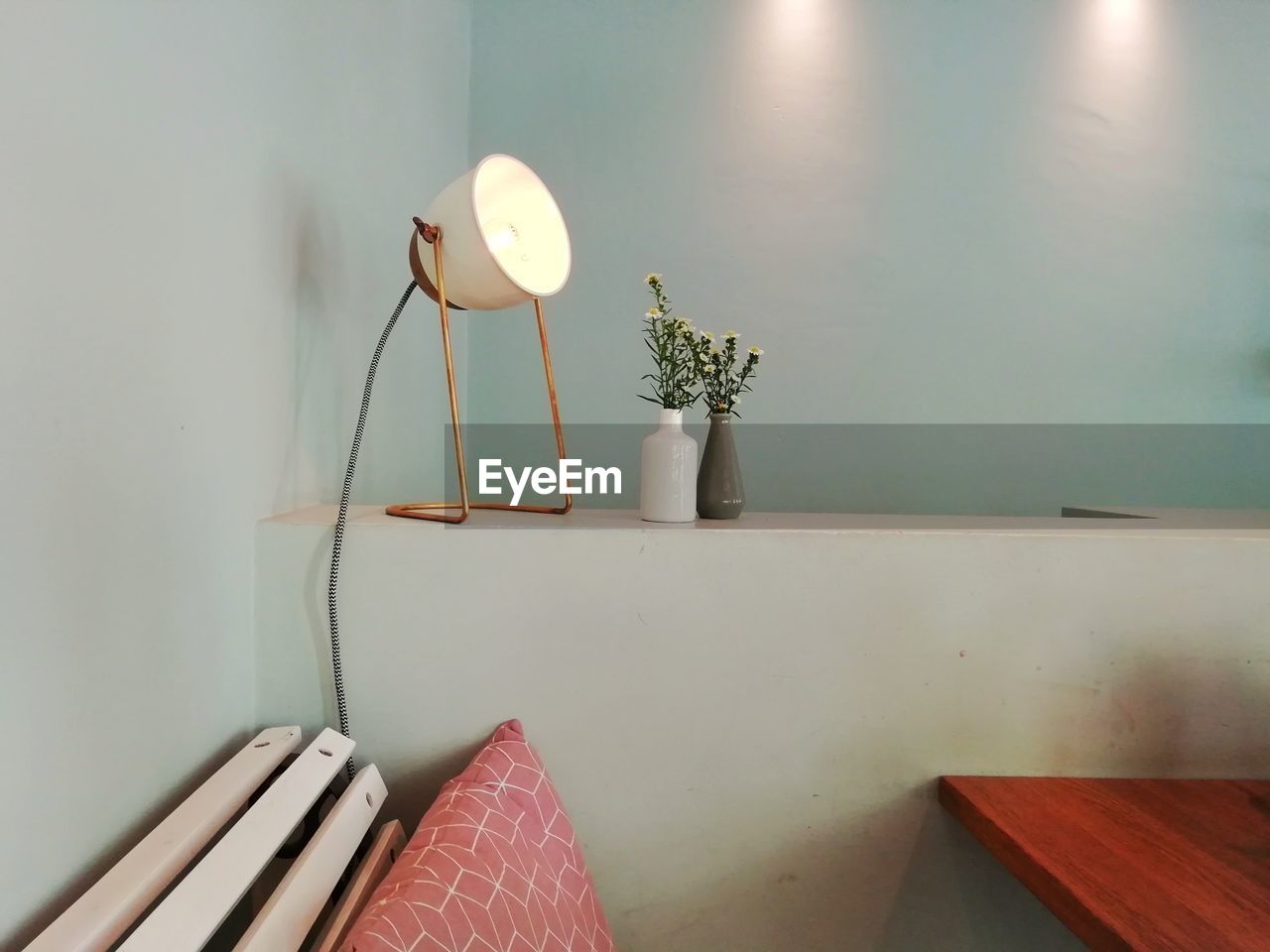 POTTED PLANT ON TABLE AGAINST ILLUMINATED WALL