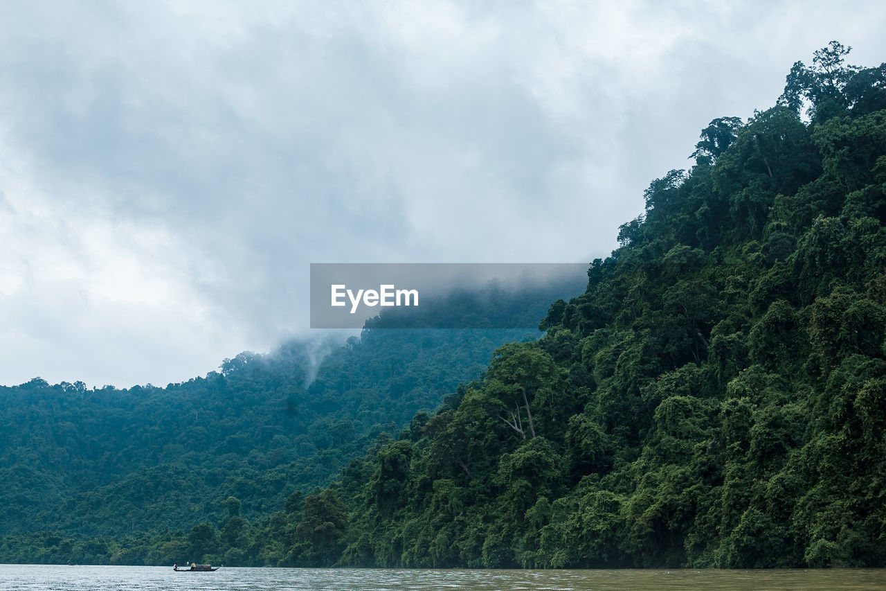 Scenic view of a single boat amid mountains against sky