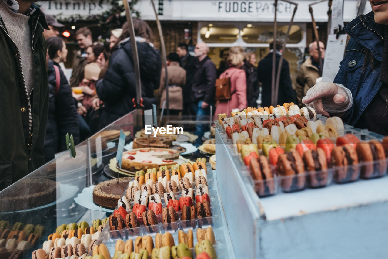 Unidentifies people buying colorful macaroons a market stall at greenwich market, london, uk.