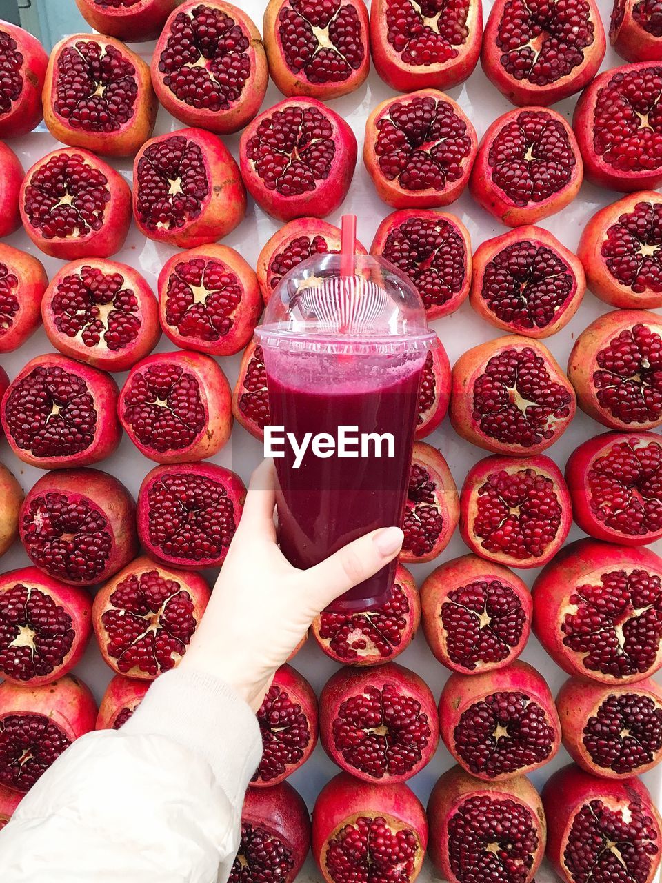 Midsection of woman holding juice against pomegranates