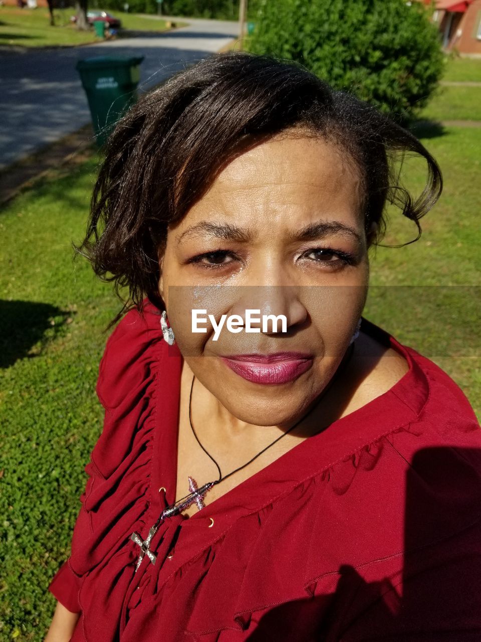 Close-up portrait of smiling mature woman standing in park during sunny day