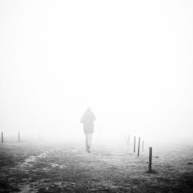 REAR VIEW OF WOMAN STANDING IN FOGGY WEATHER