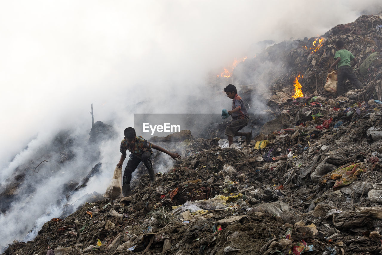 Boys on garbage burning at junkyard