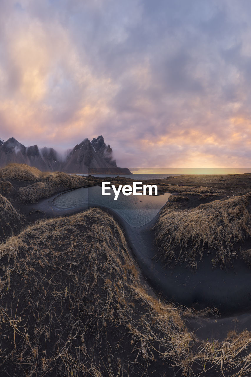 Mountain range against cloudy sky during sunset near black sand beach in iceland