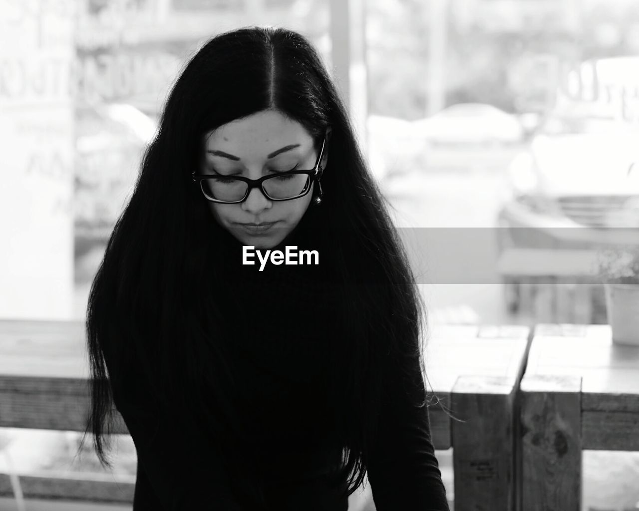 Depressed woman wearing eyeglasses while sitting at cafe