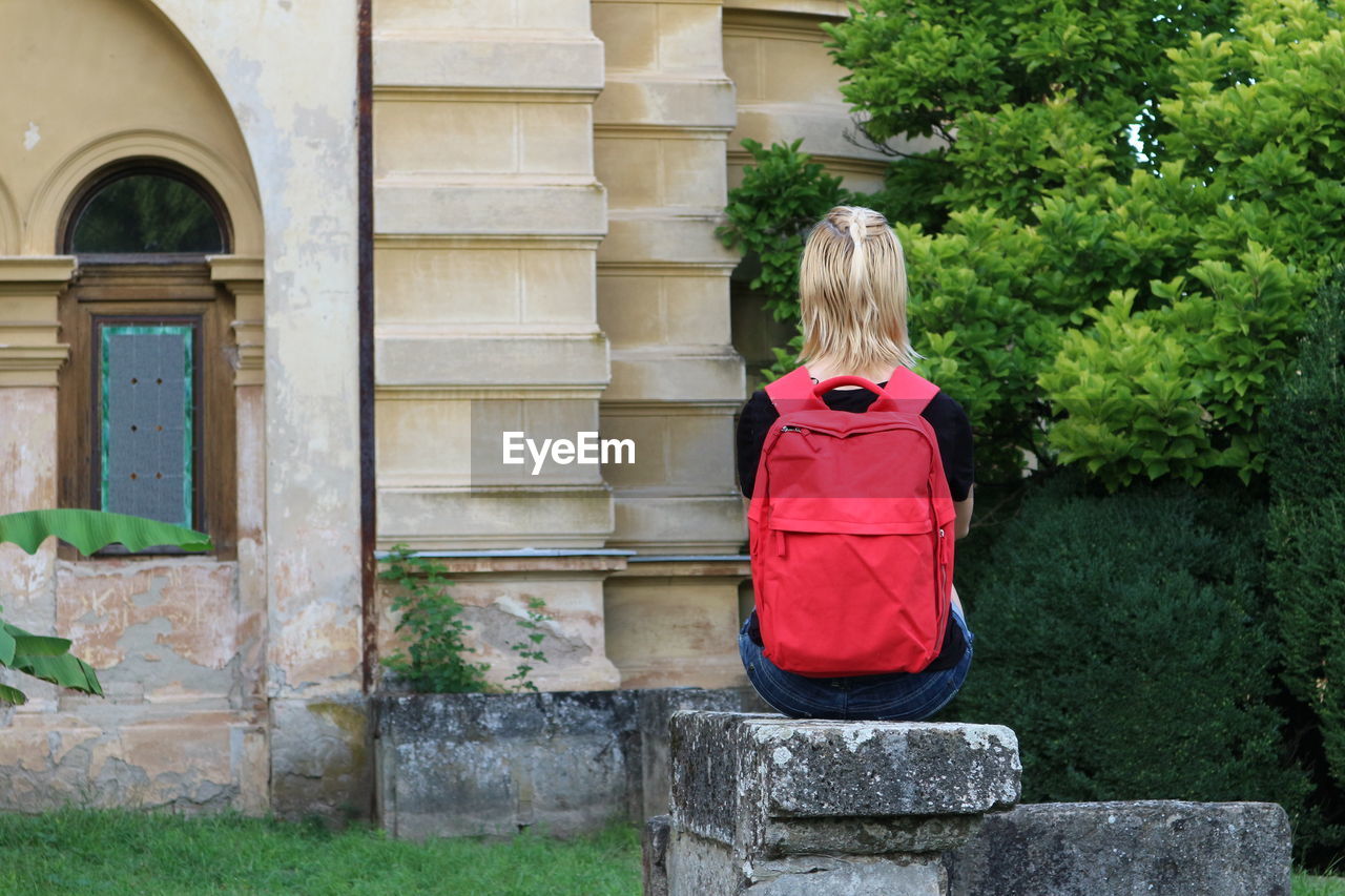 Rear view of woman sitting on rock by castle