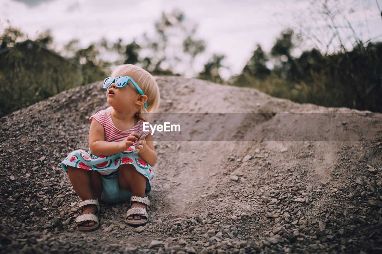 Cute baby girl crouching on sand