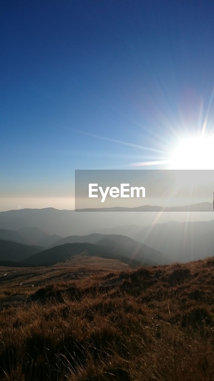 SUN SHINING THROUGH CLOUDS OVER MOUNTAINS