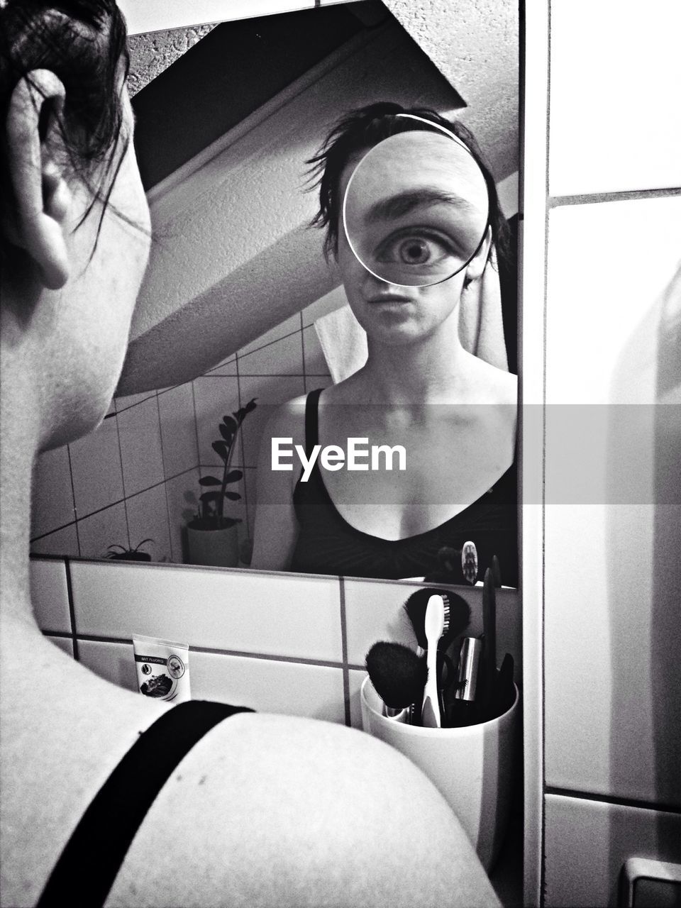 Reflection of young woman in mirror with magnified eye