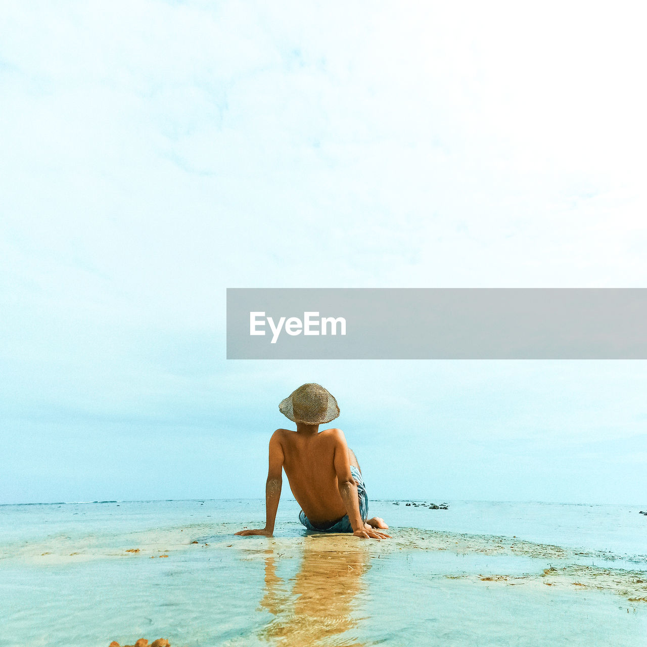Rear view of shirtless man in sea against sky