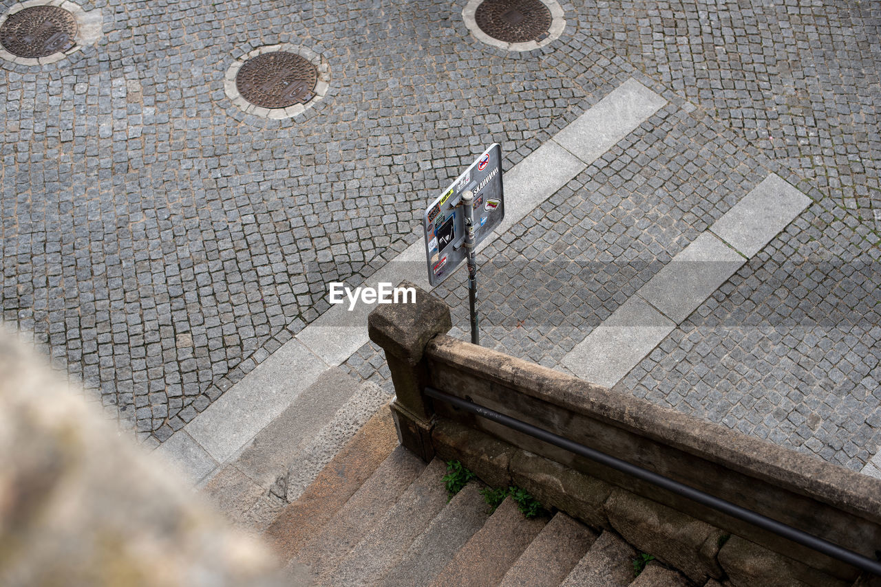 Top view of the street with paving stones, stone stairs and road sign. urban background