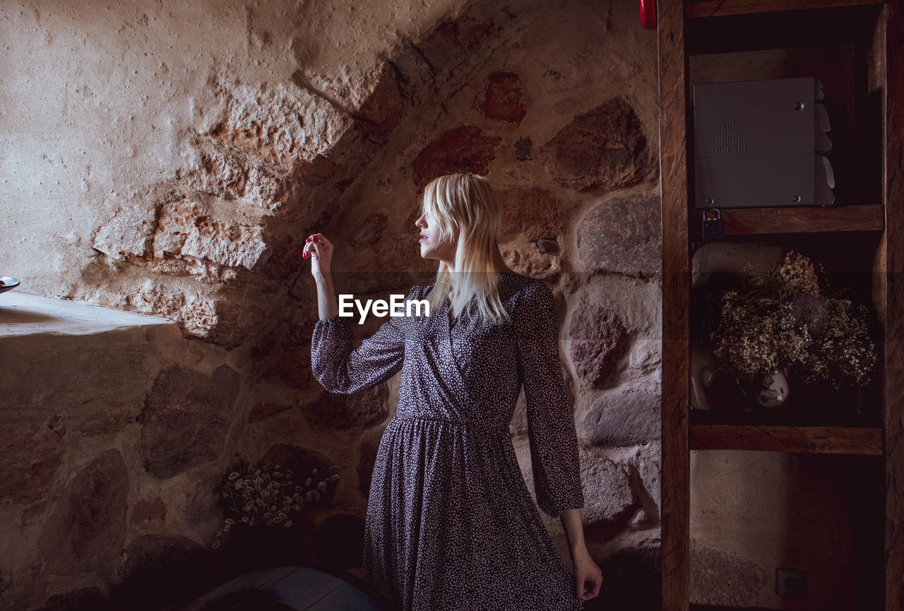 Woman standing against wall at home