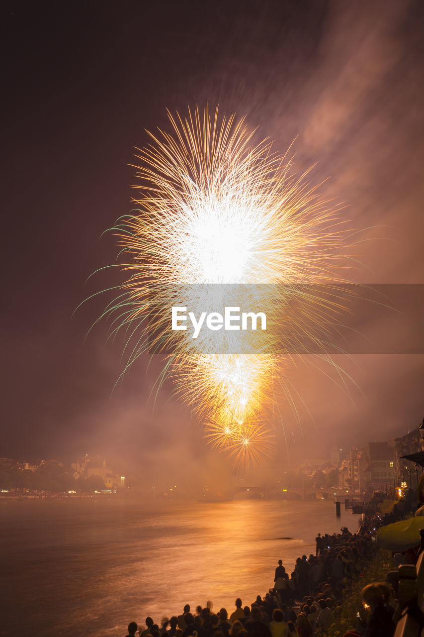 LOW ANGLE VIEW OF FIREWORK DISPLAY OVER SEA AT NIGHT