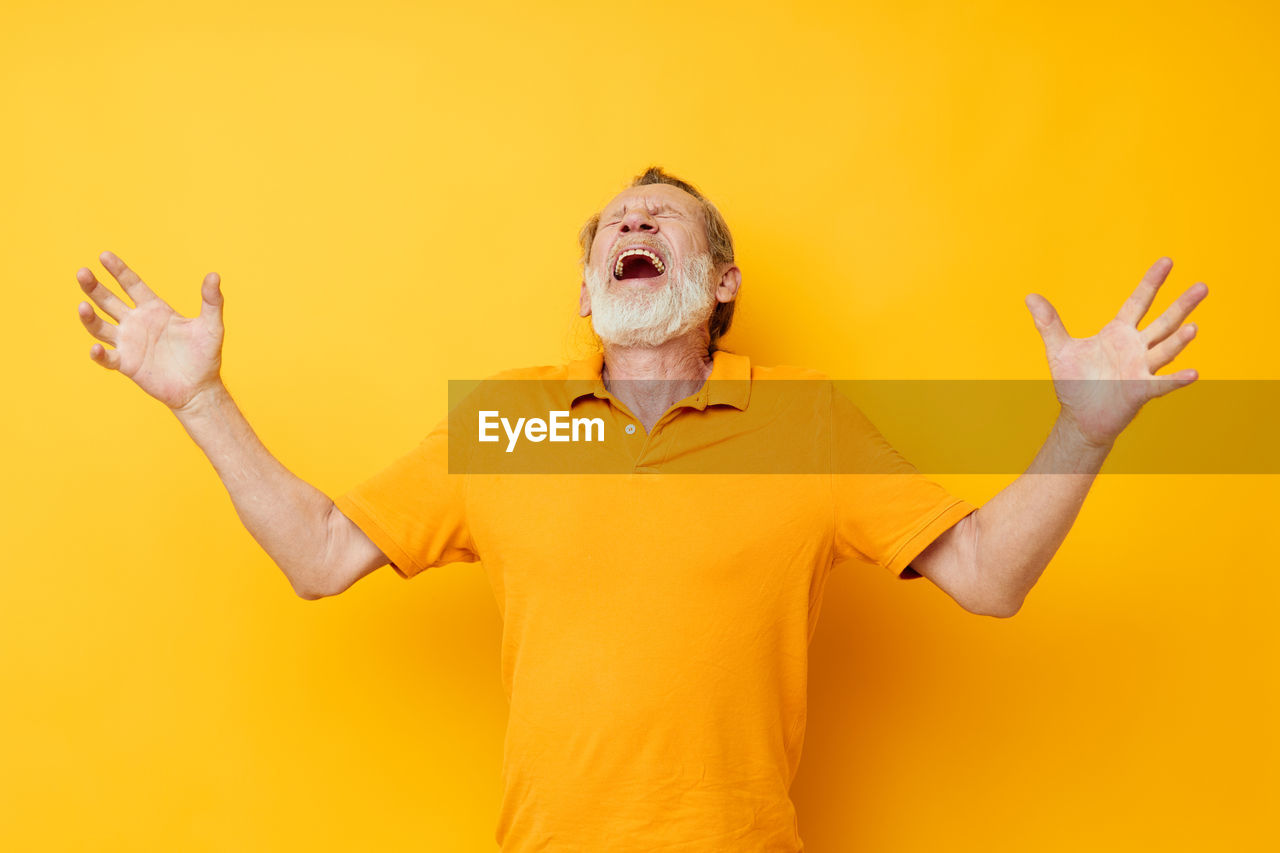 Rear view of woman gesturing against yellow wall