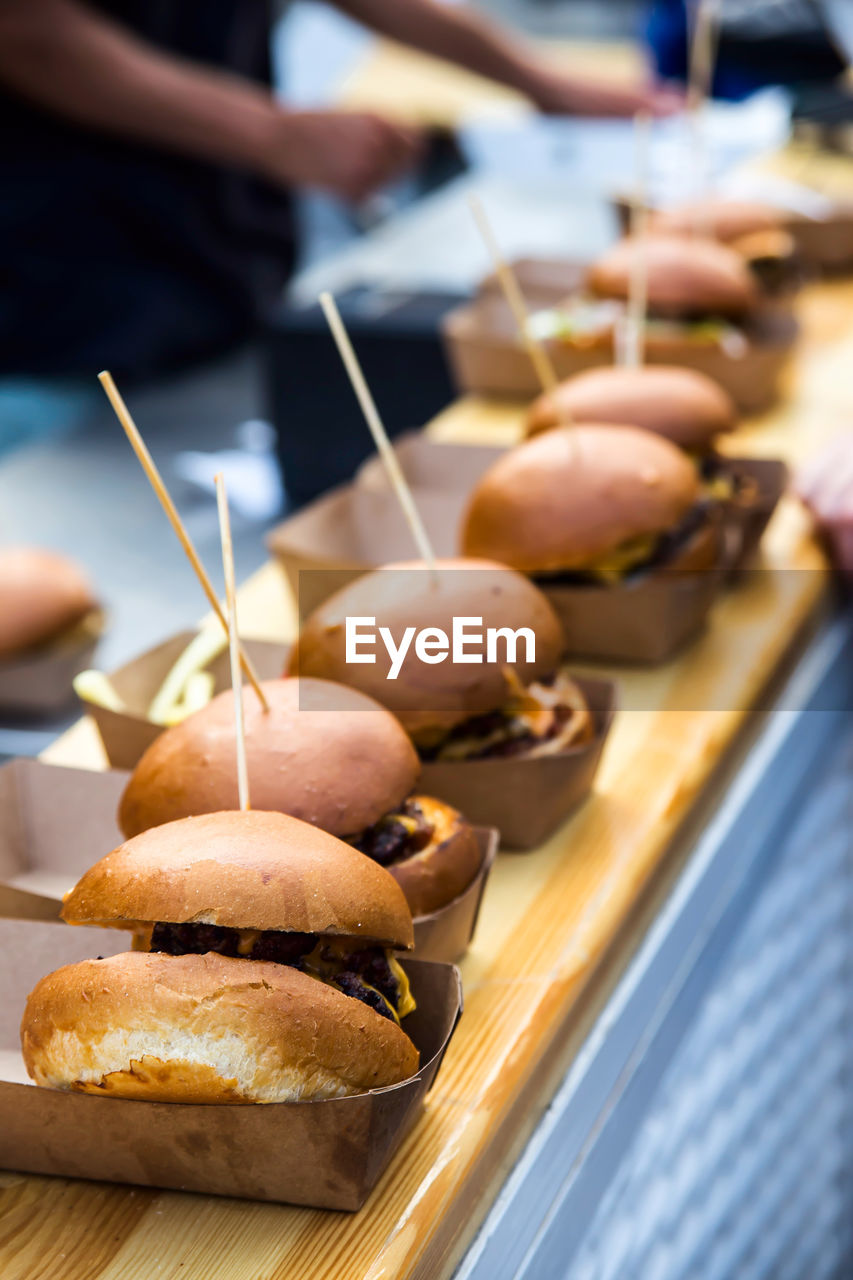 Street food many burgers with meat and cheese and french fries in craft packaging. 